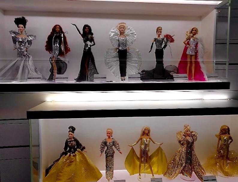Barbie's in goudkleurige kledij en zwart/wit/zilver kledij op een rij