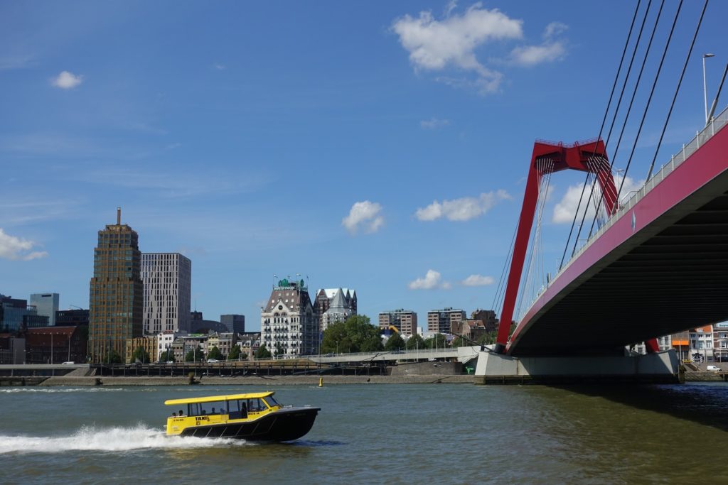 Rode Willemsbrug, gele watertaxi op de Nieuwe Maas en Witte Huis in de Stadsdriehoek in de verte, Rotterdam