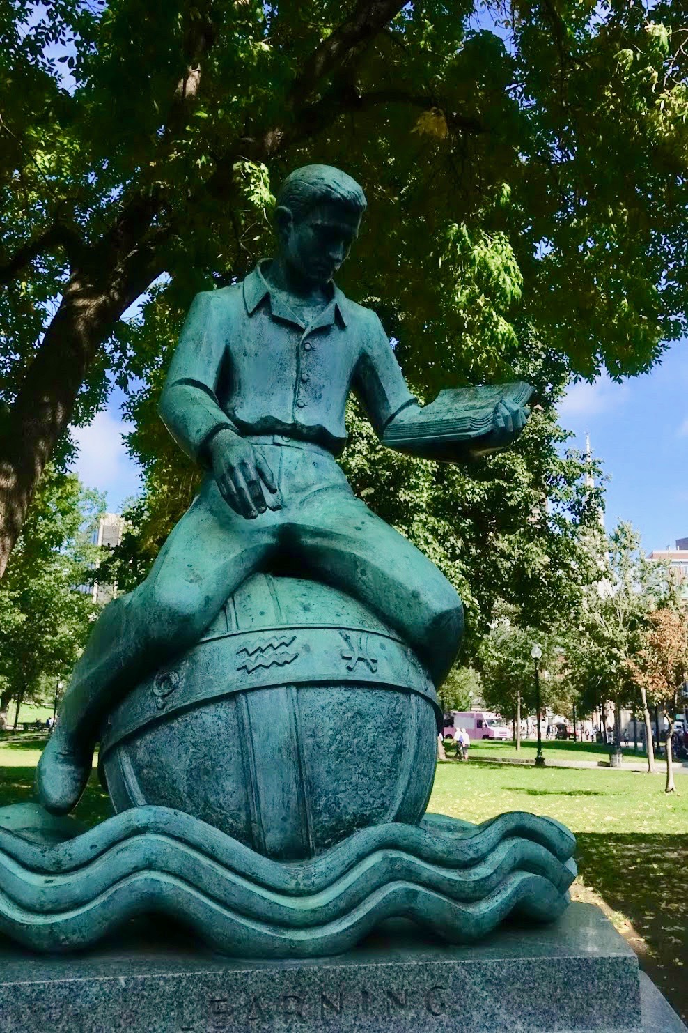 Standbeeld van jongen die leest terwijl hij op een wereldbol zit, eronder de tekst 'learning'