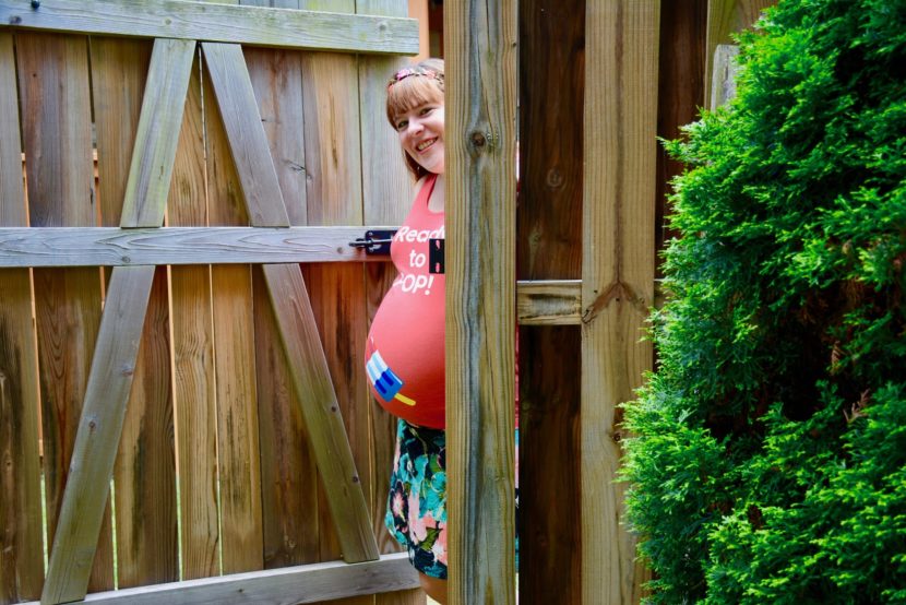zwangere vrouw voor houten poortje
