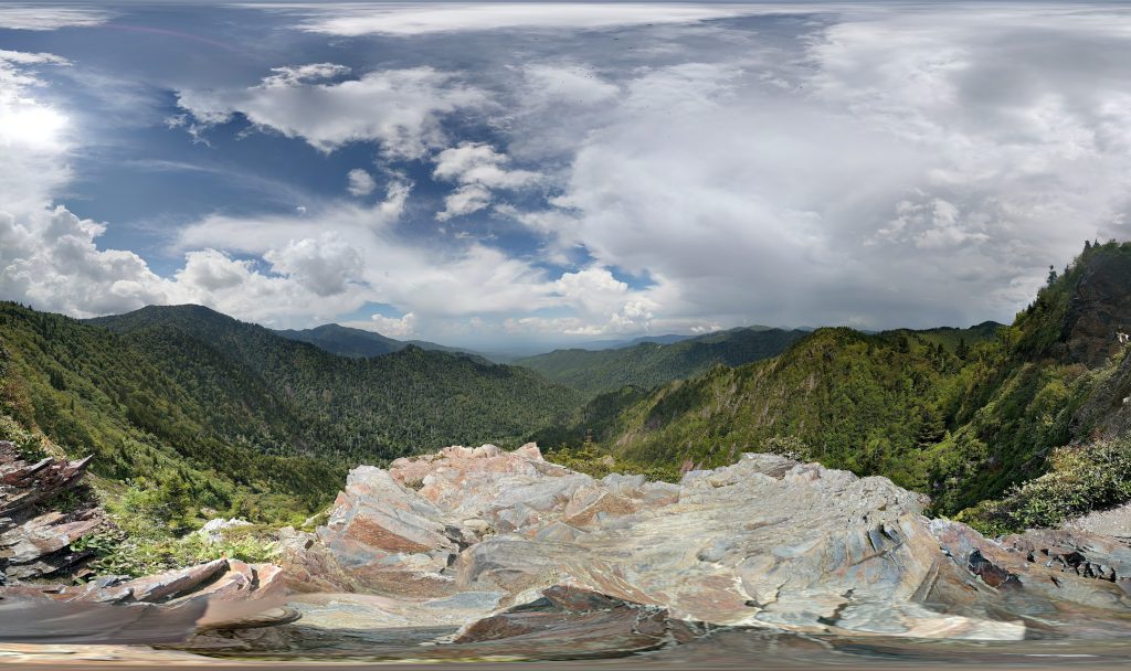 Dikke wolkpluimen over groene bergen en rots op de voorgrond, Great Smoky Mountains National Park