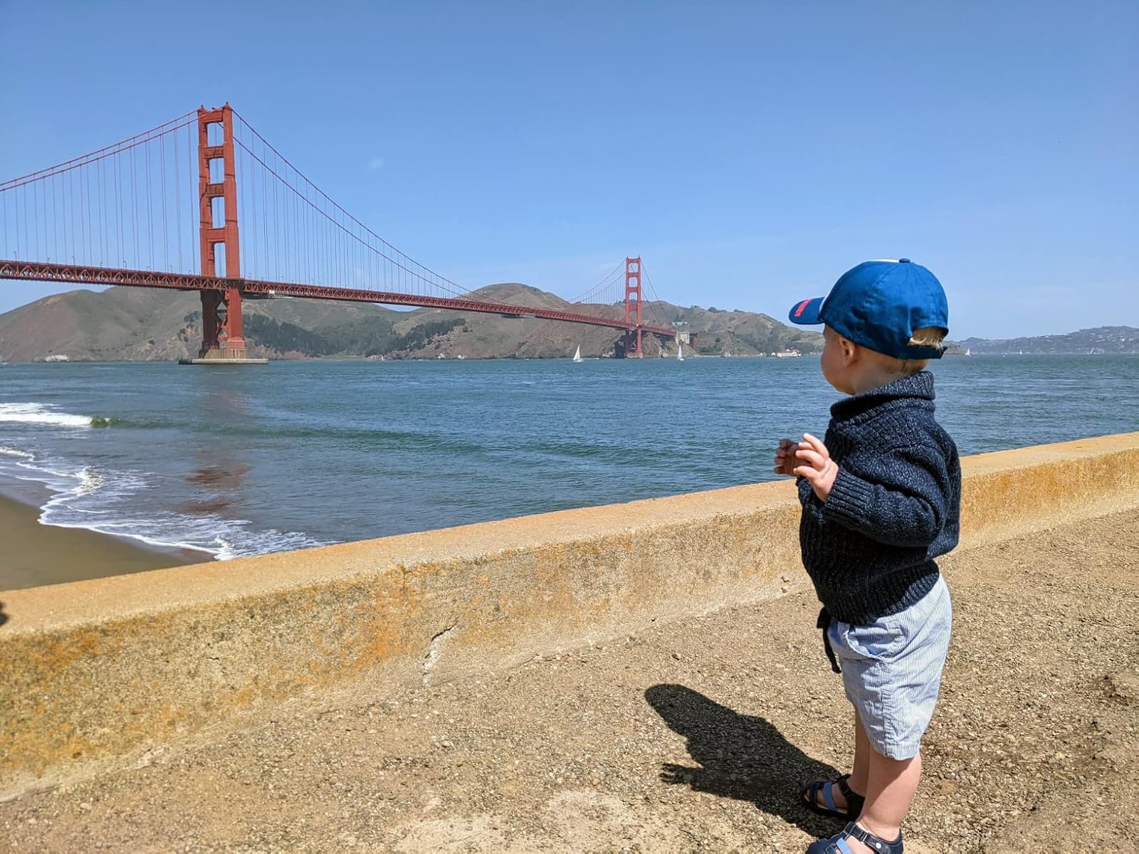 Toddler in front of San Francisco's Golden Gate Bridge with UGG brand toddler sandals